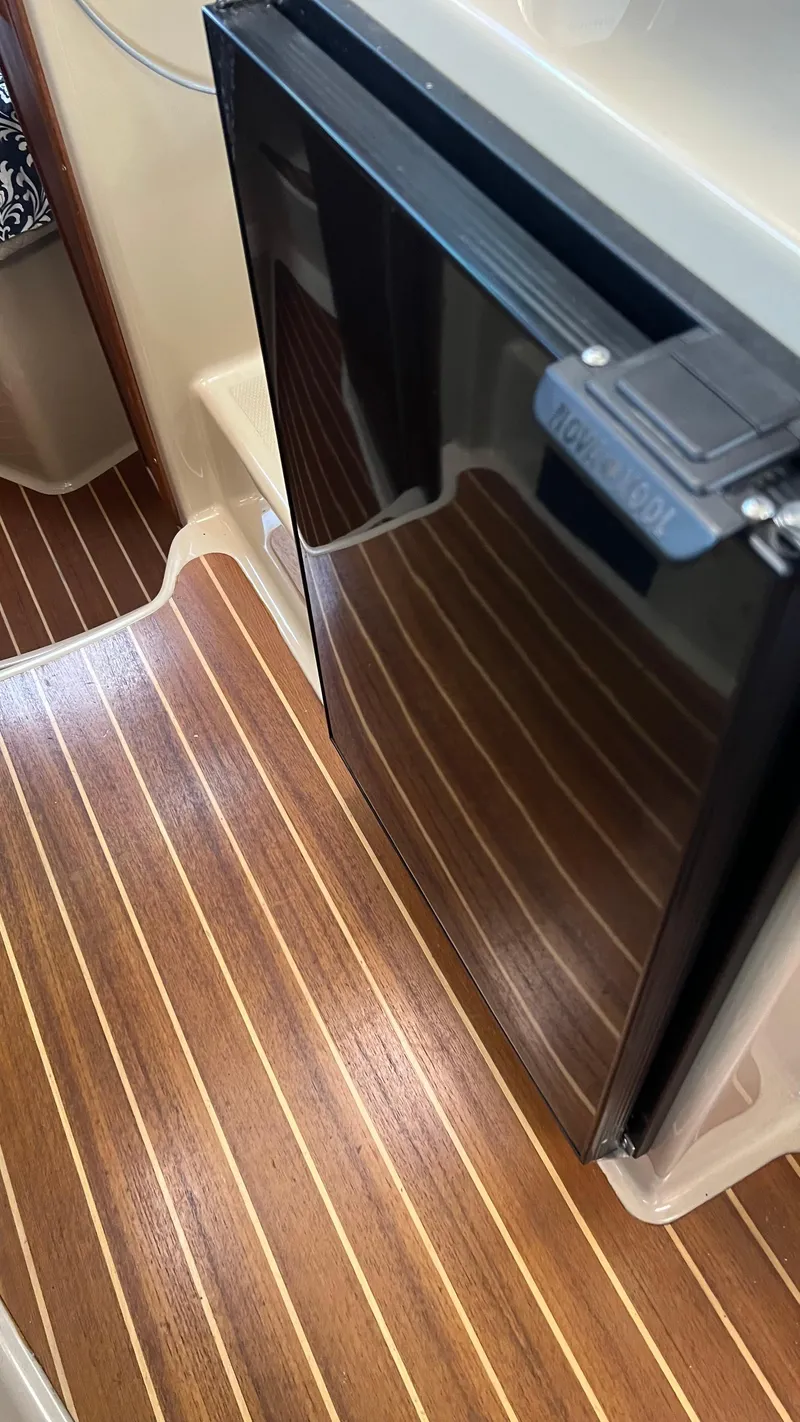 Slide: The Image of 2014 Ranger Tugs R29S interior with wood flooring and compact refrigerator. - 14