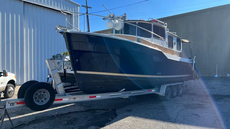 Slide: The Image of 2014 Ranger Tugs R29S boat on trailer, parked outdoors near industrial building. - 4