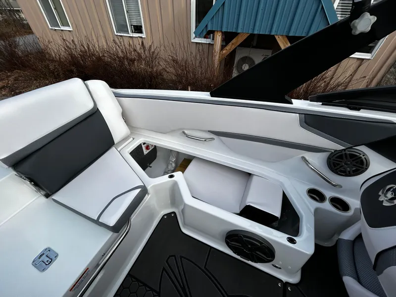 Slide: The Image of 2024 Scarab 215 Wake LE boat interior with white and black seating, storage compartments, and speakers. - 15
