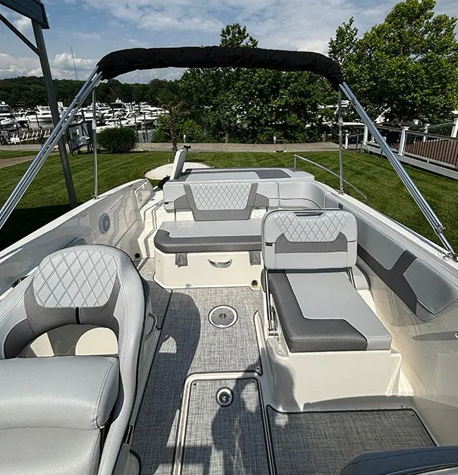 Slide: The Image of 2024 Bayliner VR6 boat interior with gray seating and open deck, docked near a marina. - 7