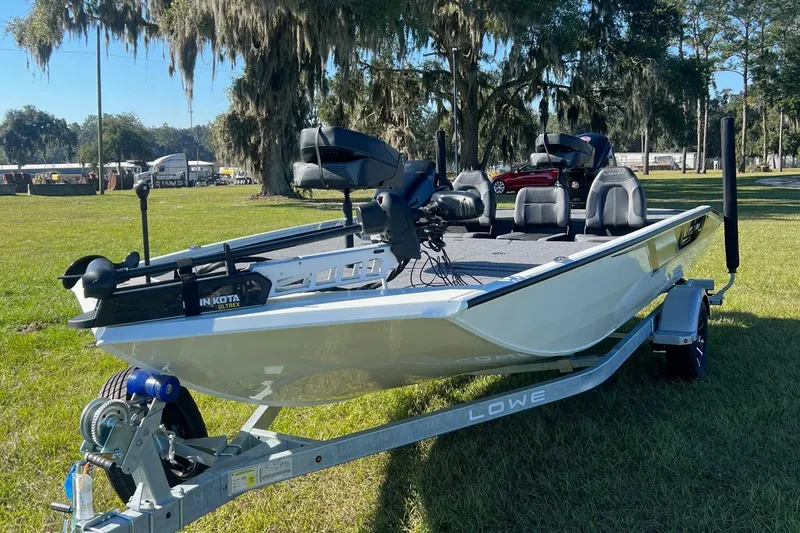 Slide: The Image of 2024 Lowe Stinger 188 SC fishing boat on trailer in grassy area. - 0