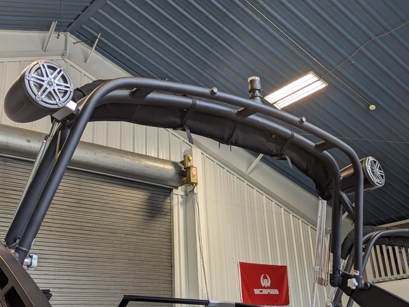 Slide: The Image of 2024 Scarab 235 ID boat with wakeboard tower and speakers in a storage facility. - 13