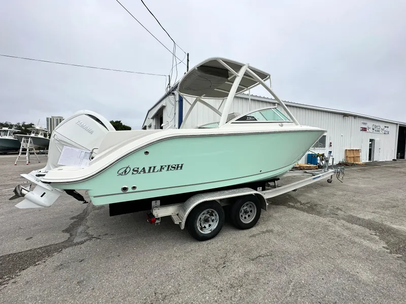 Slide: The Image of 2024 Sailfish 226 DC boat on a trailer outside a warehouse. - 19