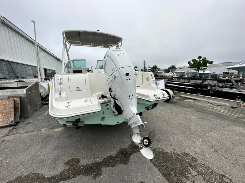 Slide: The Image of 2024 Sailfish 226 DC boat with outboard motor, docked at a marina. - 20