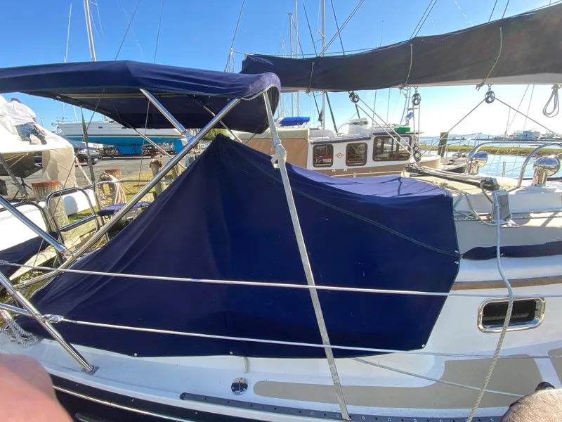 Slide: The Image of 2014 Com-Pac 27 sailboat with blue canvas cover docked at marina. - 1