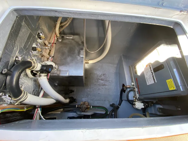 Slide: The Image of Engine compartment of a 2014 Com-Pac 27 sailboat with various mechanical components. - 13