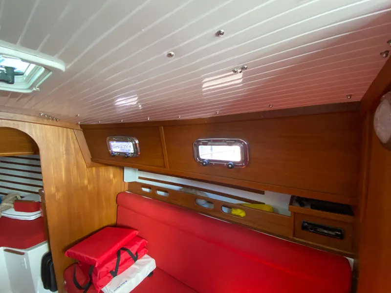 Slide: The Image of Interior cabin of 2014 Com-Pac 27 sailboat with red seating and wooden storage cabinets. - 15
