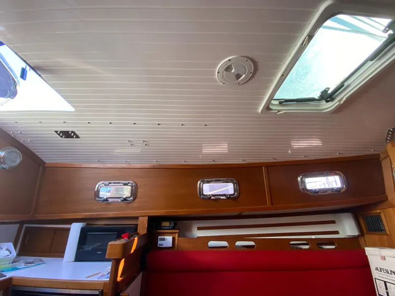 Slide: The Image of Interior cabin of 2014 Com-Pac 27 sailboat with wooden cabinetry and red seating. - 16