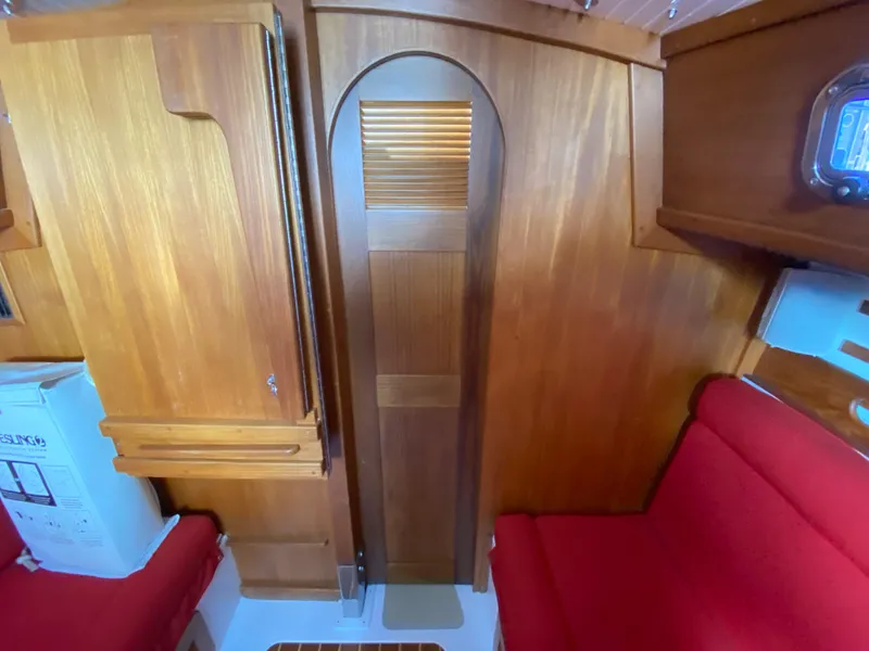 Slide: The Image of Interior of 2014 Com-Pac 27 sailboat with wooden cabinetry and red seating. - 23
