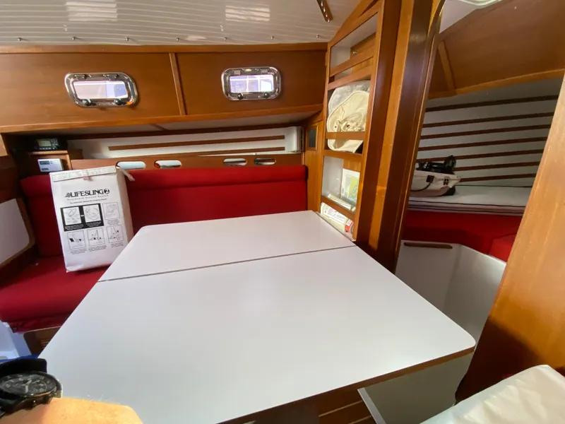 Slide: The Image of Interior of 2014 Com-Pac 27 sailboat with red seating and white table. - 26