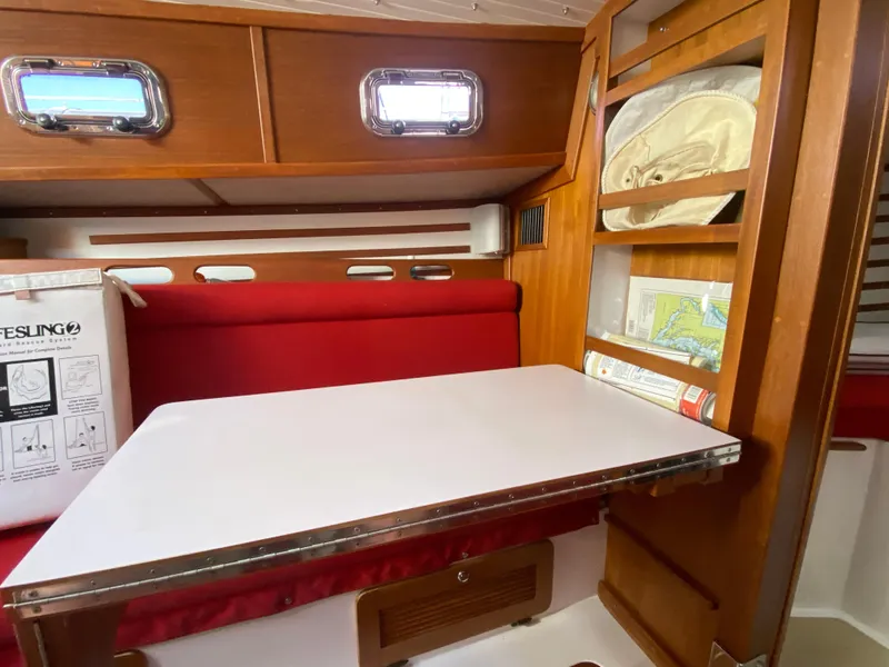 Slide: The Image of Interior of 2014 Com-Pac 27 sailboat with red seating and white table. - 27