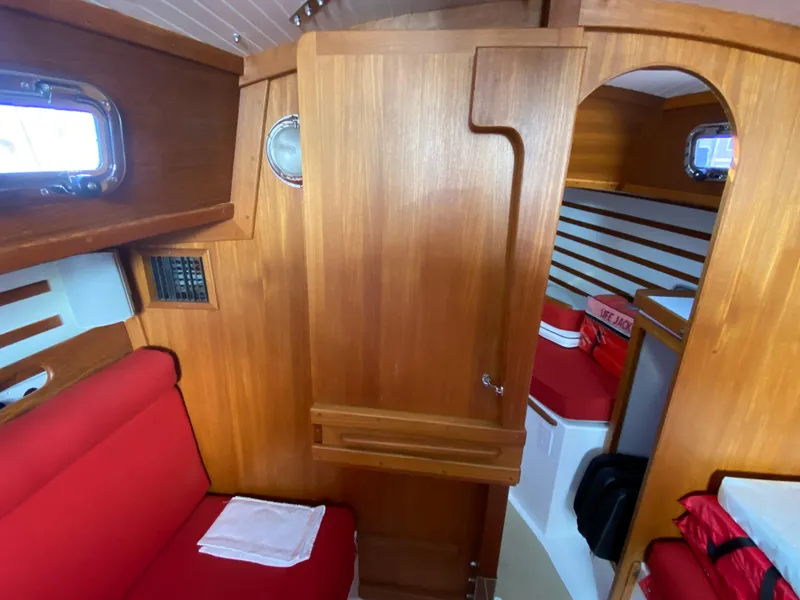 Slide: The Image of Interior of 2014 Com-Pac 27 sailboat with wooden cabinetry and red seating. - 28
