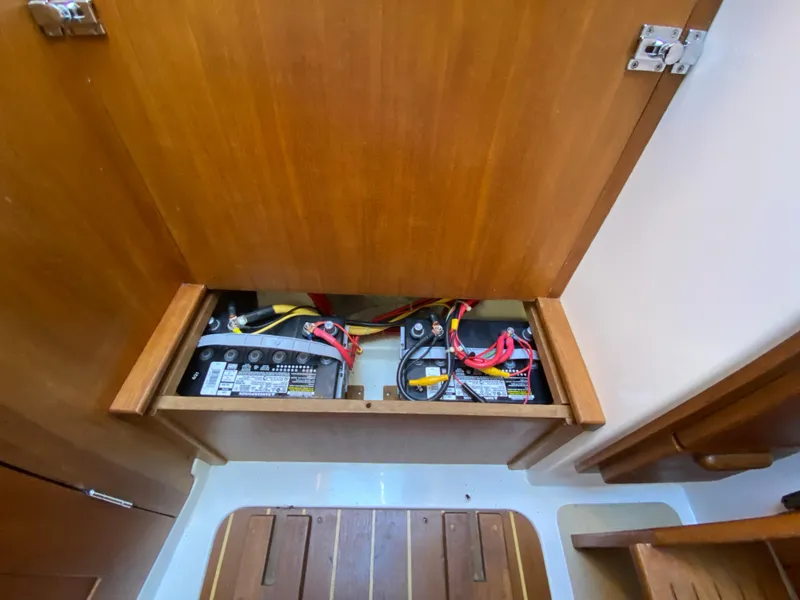 Slide: The Image of Battery compartment of a 2014 Com-Pac 27 sailboat with wiring and wooden paneling. - 36