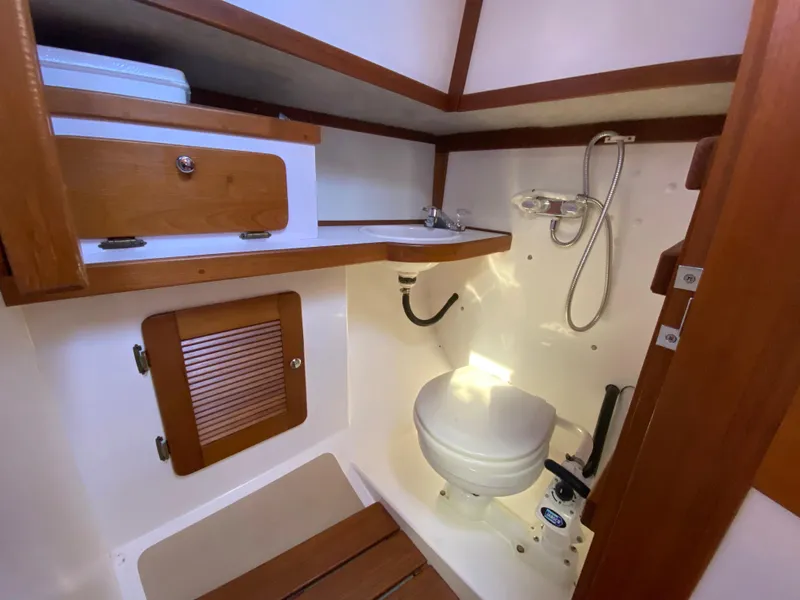 Slide: The Image of 2014 Com-Pac 27 sailboat bathroom with toilet, sink, and wooden storage cabinets. - 40
