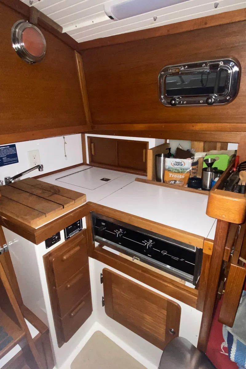 Slide: The Image of 2014 Com-Pac 27 sailboat galley with wooden cabinetry and modern appliances. - 48