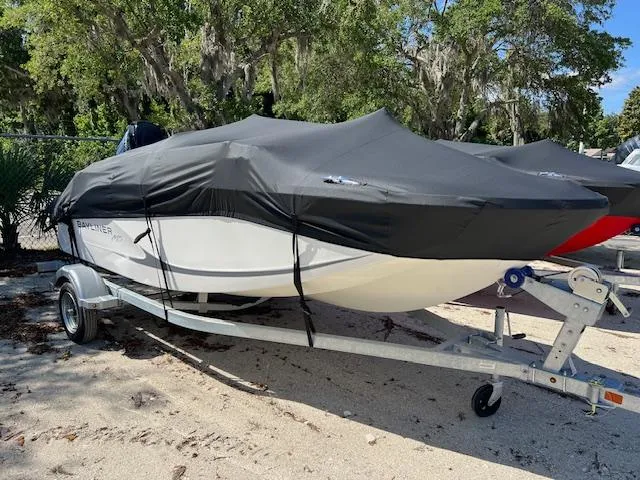 The Image of 2024 Bayliner Element M15 boat covered on a trailer, parked outdoors. - 0