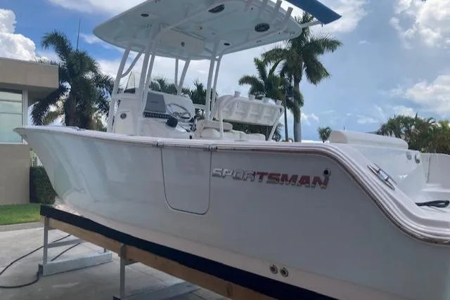 Slide: The Image of 2014 Sportsman Heritage 251 Center Console boat on a lift with palm trees in the background. - 2