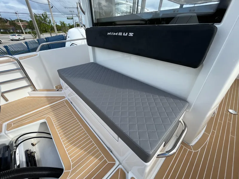 Slide: The Image of 2024 Nimbus Commuter 9 #136 boat seating area with cushioned bench and teak deck. - 7