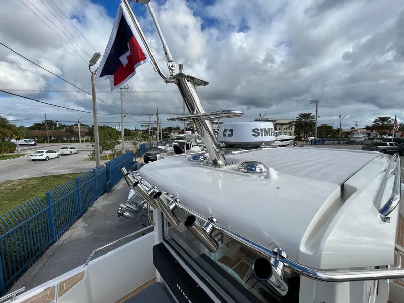 Slide: The Image of 2024 Nimbus Commuter 9 #136 boat with radar and flag, docked under cloudy sky. - 9
