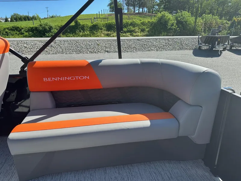 Slide: The Image of 2025 Bennington 21 SSR Quad Bench with orange and gray seating, outdoors. - 10