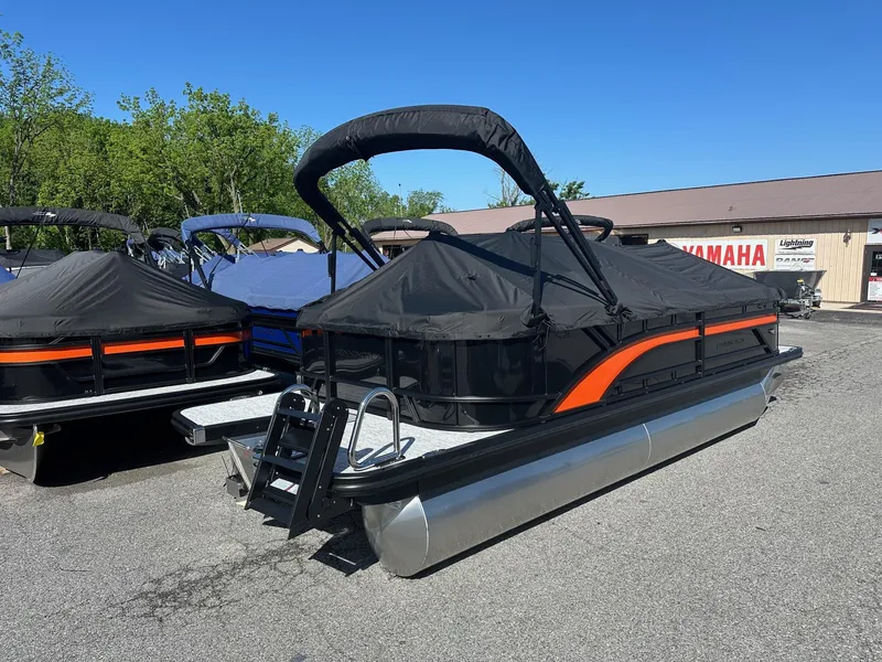 Slide: The Image of 2025 Bennington 21 SSR Quad Bench pontoon boat with cover, parked outdoors. - 21