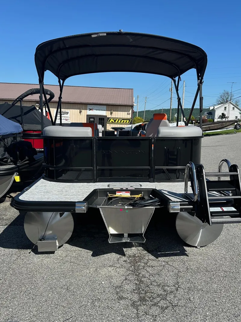 Slide: The Image of 2025 Bennington 21 SSR Quad Bench pontoon boat with canopy, parked outdoors. - 4