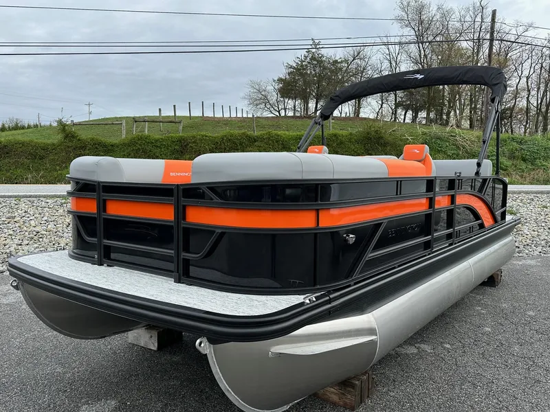 The Image of 2025 Bennington 22 SSB Swing Back pontoon boat with orange and gray accents, parked outdoors. - 1