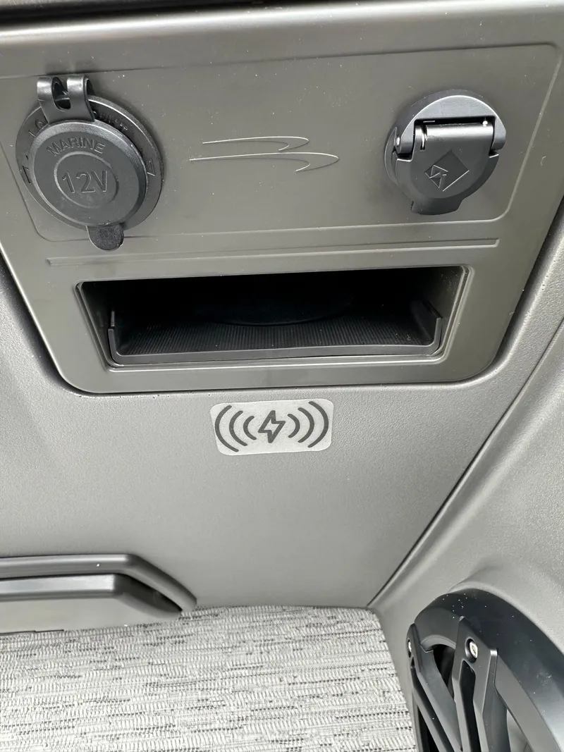 Slide: The Image of 2025 Bennington 22 SSB Swing Back dashboard with 12V marine outlet and wireless charging symbol. - 26