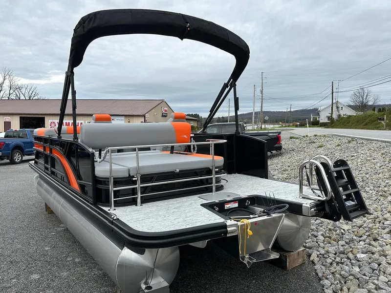 Slide: The Image of 2025 Bennington 22 SSB Swing Back pontoon boat with orange and gray seating, docked outdoors. - 7