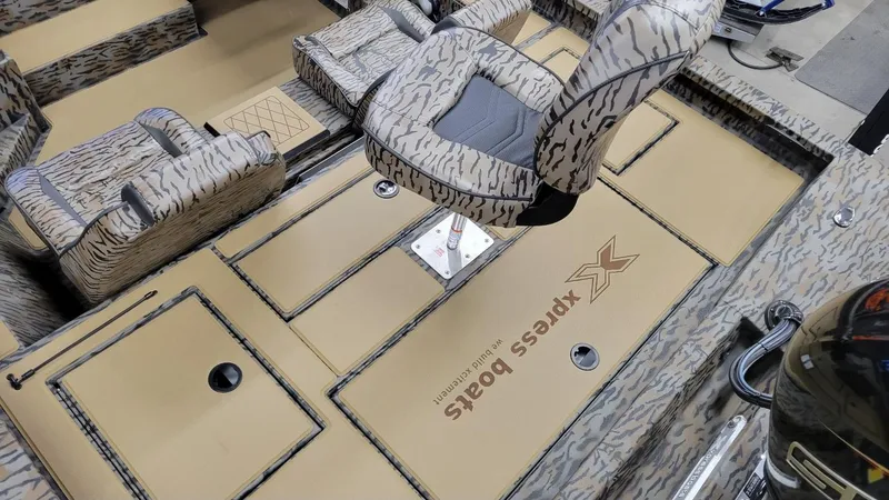 Slide: The Image of 2025 Xpress H18 Bass boat interior with camo seating and storage compartments. - 16