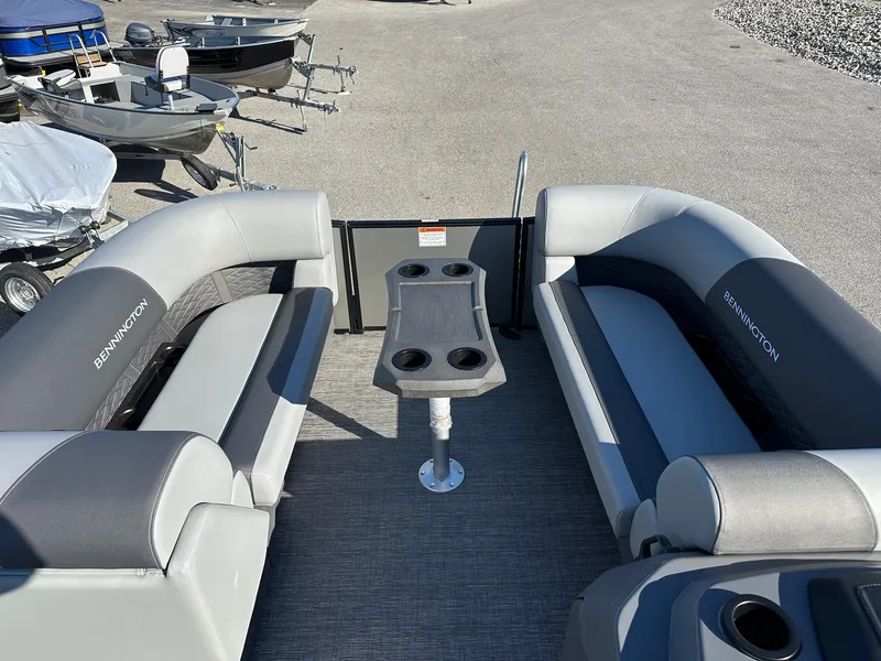 Slide: The Image of 2025 Bennington 20 SSB Tritoon interior with seating and table, parked with other boats. - 10