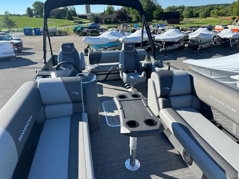 Slide: The Image of 2025 Bennington 20 SSB Tritoon interior with seating and table, parked outdoors. - 23
