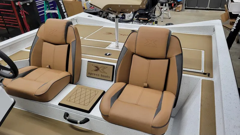 Slide: The Image of 2025 Xpress H18C Crappie boat interior with tan seats and steering wheel. - 14