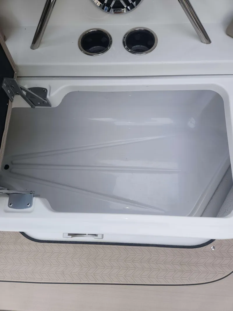 Slide: The Image of Open storage compartment on 2024 Hurricane 2600 SD boat with cup holders and speaker. - 6