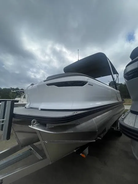 The Image of 2024 Manitou 22 Cruise FLEBRF Stealth pontoon boat on trailer. - 1