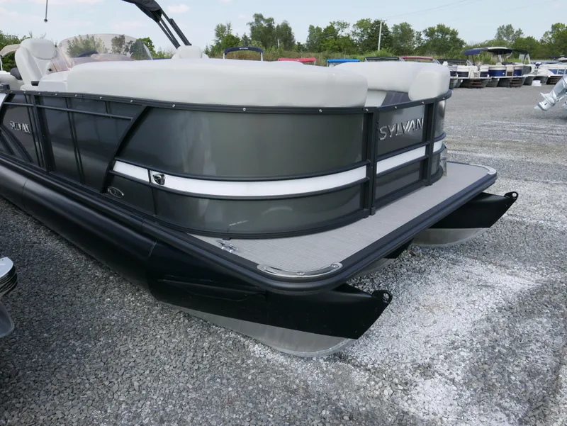 Slide: The Image of 2023 Sylvan Mirage X X3 pontoon boat, sleek design, parked on gravel lot. - 2