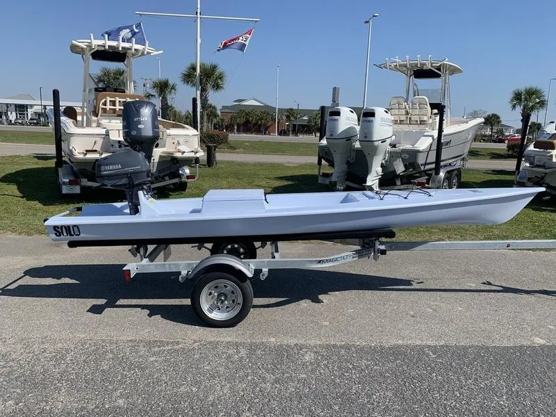 Slide: The Image of 2023 Solo Skiff 14 on trailer, with Yamaha outboard motor, parked near other boats. - 4