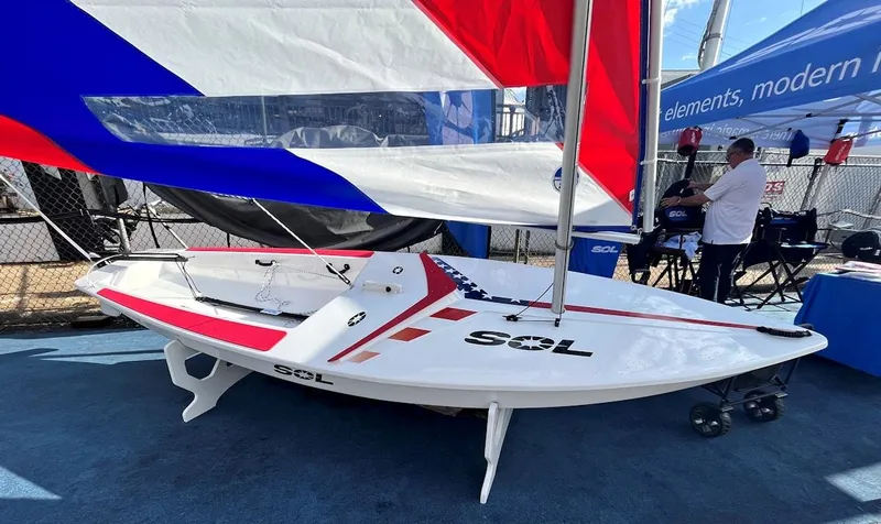 Slide: The Image of 2024 Dinghy Sol Sailboat on display with colorful sails at a boat show. - 13