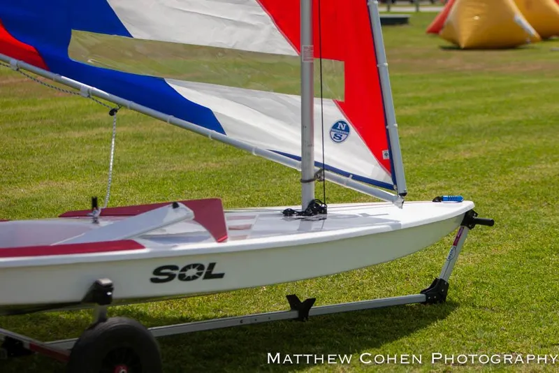Slide: The Image of 2024 Dinghy Sol Sailboat on grass with colorful sails. - 17