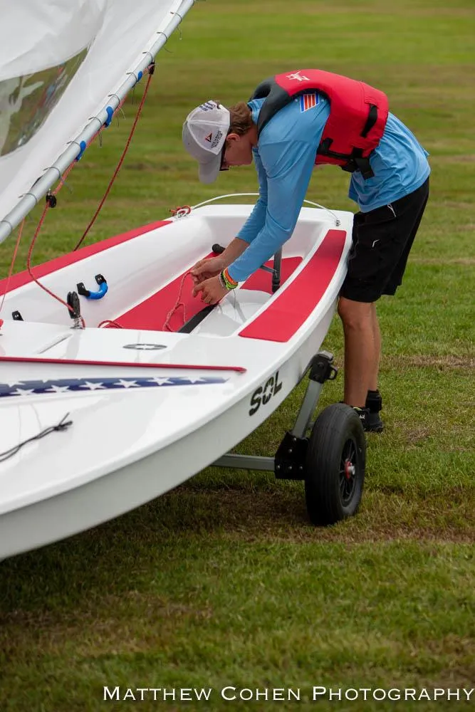 Slide: The Image of Person preparing 2024 Dinghy Sol Sailboat on grassy field. - 18