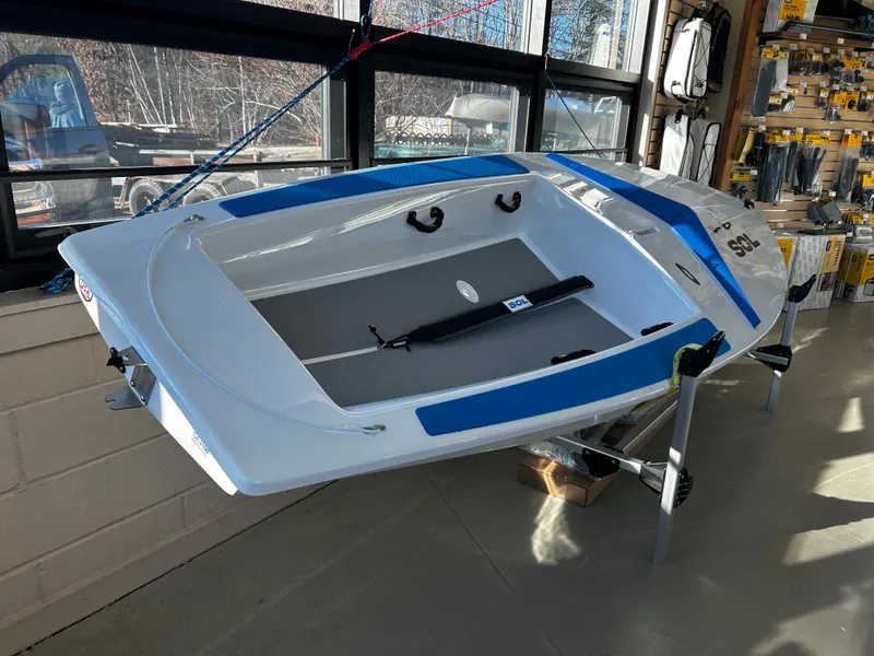 Slide: The Image of 2024 Dinghy Sol Sailboat displayed indoors, featuring a sleek white and blue design. - 5