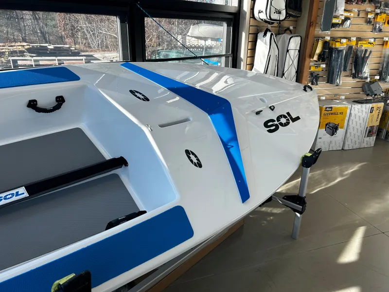 Slide: The Image of 2024 Dinghy Sol Sailboat in showroom, white with blue accents. - 8