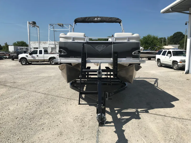 Slide: The Image of 2024 Avalon VTX Cruise pontoon boat on trailer, parked outside a metal building. - 2