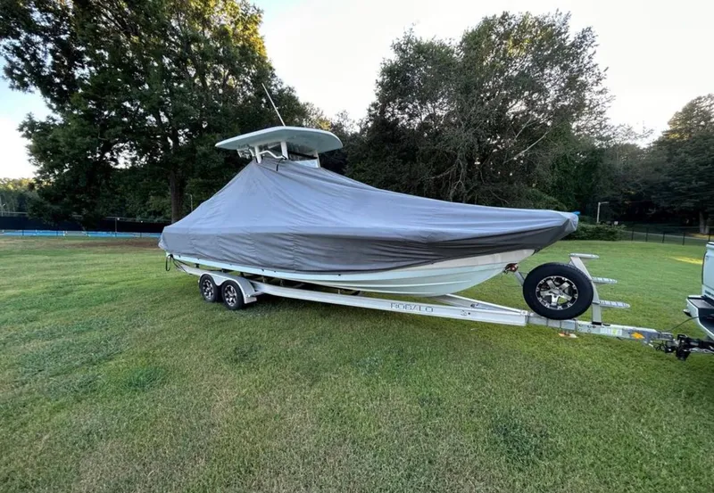 Slide: The Image of 2019 Robalo 246 Cayman boat on trailer with cover in grassy area. - 13