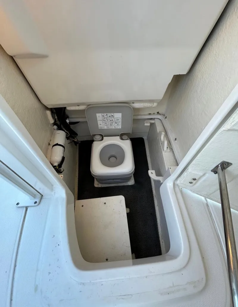 Slide: The Image of 2019 Robalo 246 Cayman boat interior with a compact marine toilet. - 14