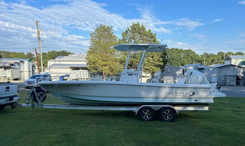 Slide: The Image of 2019 Robalo 246 Cayman boat on a trailer in a grassy area. - 2