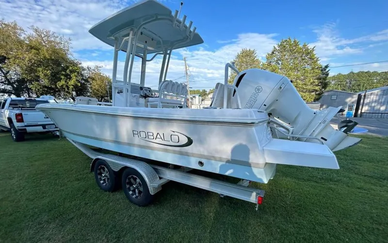 Slide: The Image of 2019 Robalo 246 Cayman boat on a trailer, parked on grass. - 3