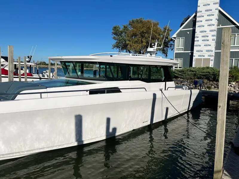 The Image of 2024 Axopar 45 XC Cross Cabin boat docked in marina under clear blue sky. - 0