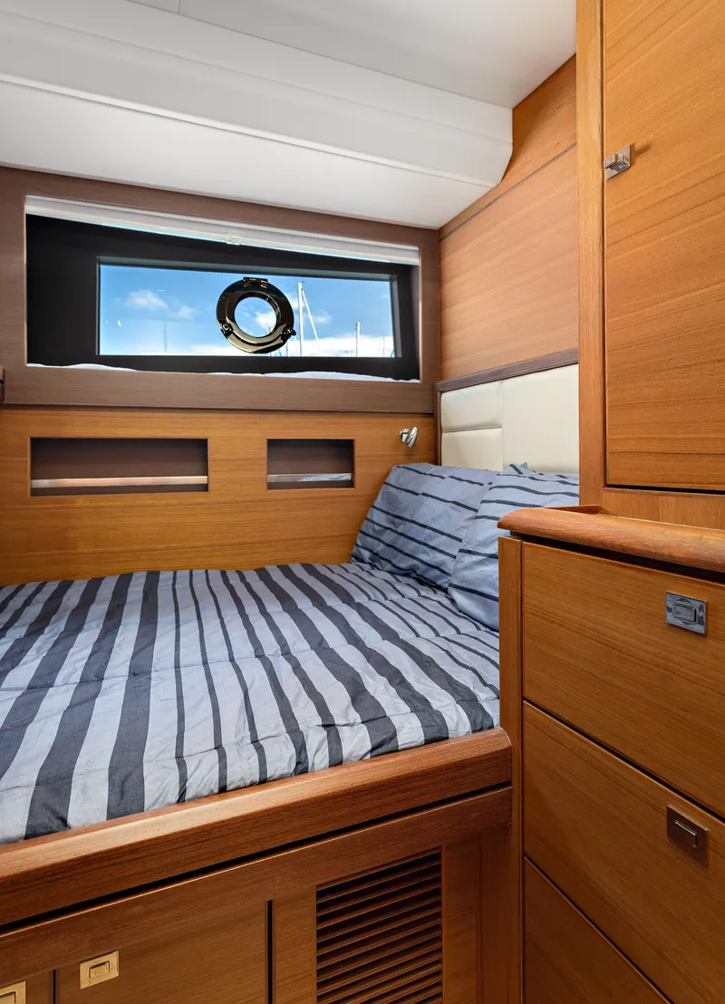 Slide: The Image of 2025 North Pacific 450 Pilothouse cabin with striped bedding and wooden interior. - 15