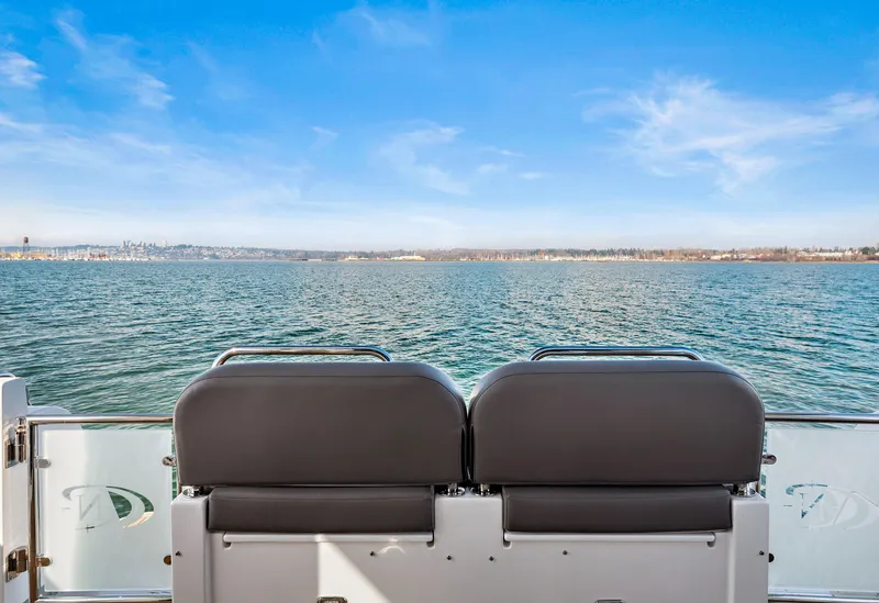 Slide: The Image of 2025 North Pacific 450 Pilothouse boat, rear view of seats overlooking calm water. - 31